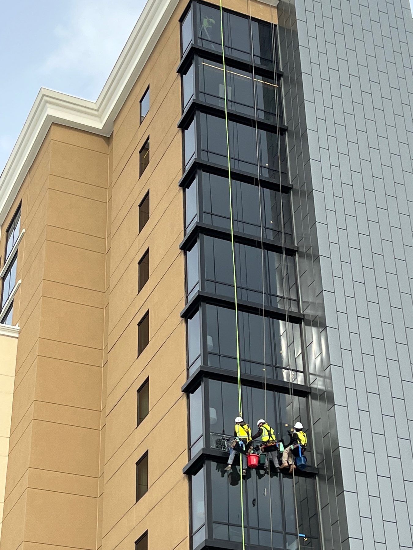 Artisan rope-access team cleaning a hotel facade